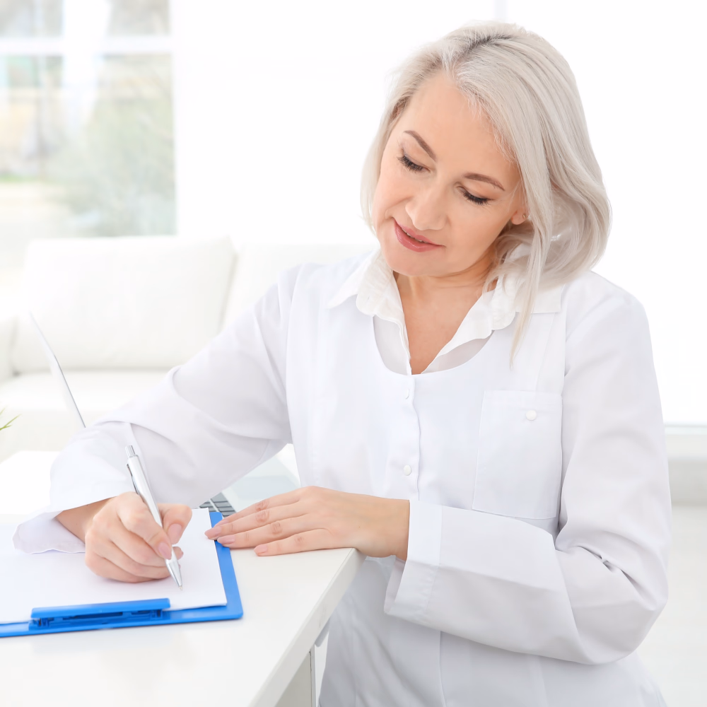 Female doctor completing patient referral paperwork at her desk