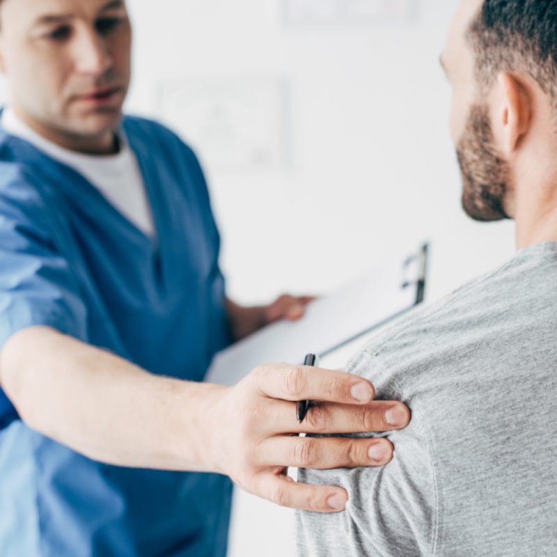 Doctor examining a patient's shoulder during a consultation for pain