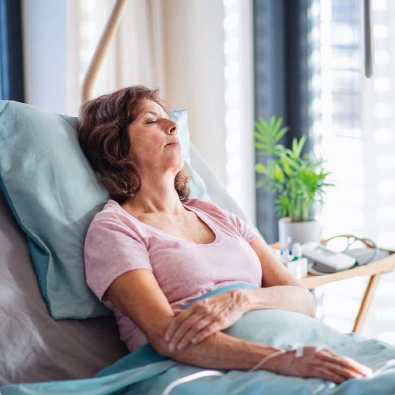 Woman speaking with a healthcare provider while resting in a hospital bed