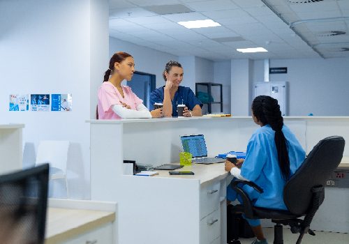 Healthcare professionals speaking with patients at a medical reception desk