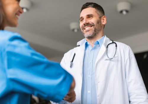 Smiling male healthcare professional wearing a white coat and stethoscope