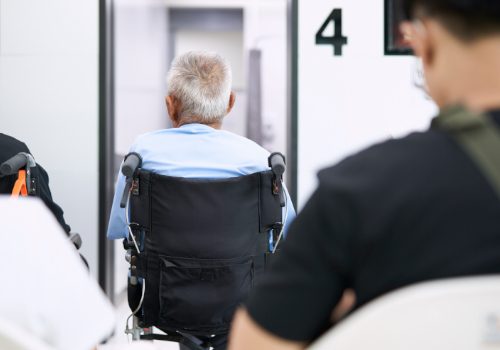 Patient in a wheelchair waiting near an elevator at a medical facility